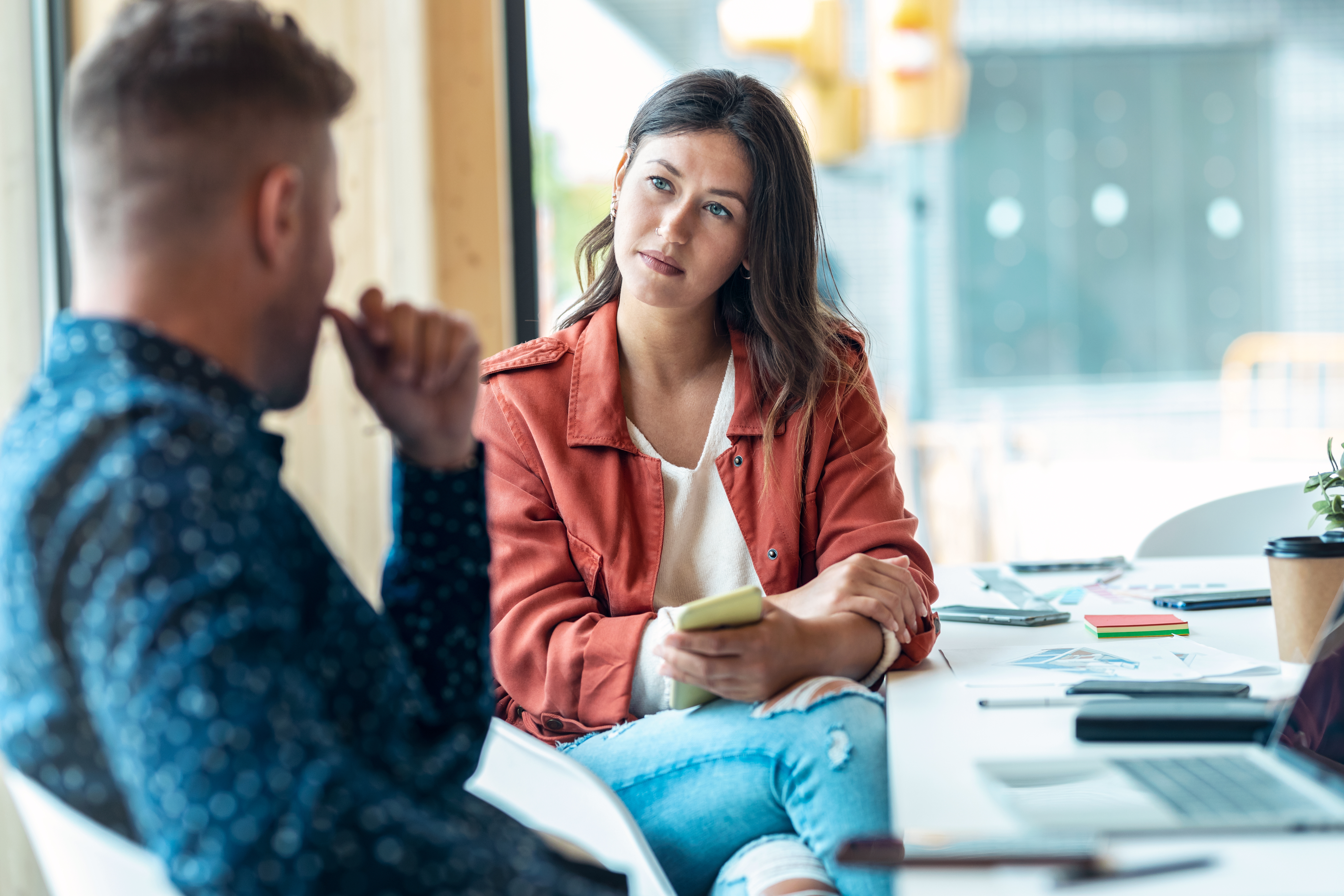 Zwei Personen sitzen am Schreibtisch und führen ein Gespräch.